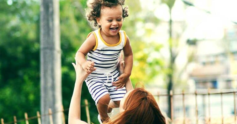 mujer lanzando al aire a un sonriente niño