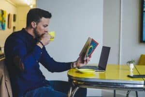 Hombre leyendo un libro y tomando café