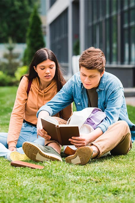 pareja de estudiantes leyendo al aire libre