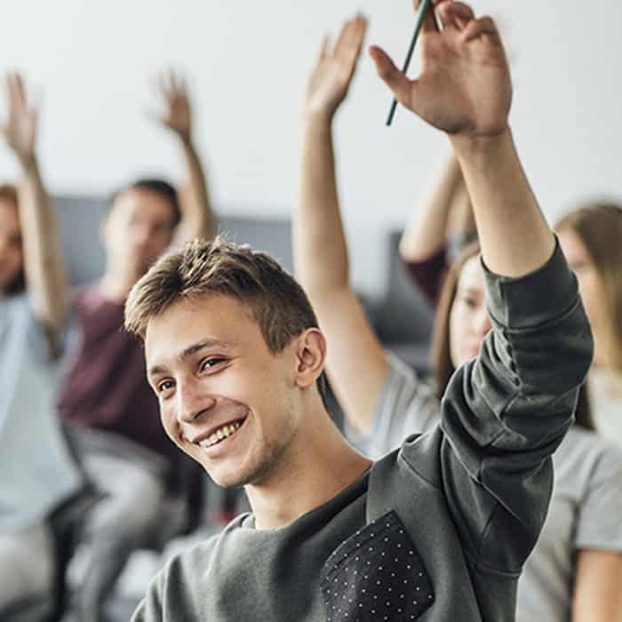 joven levantando la mano en el salon de clases