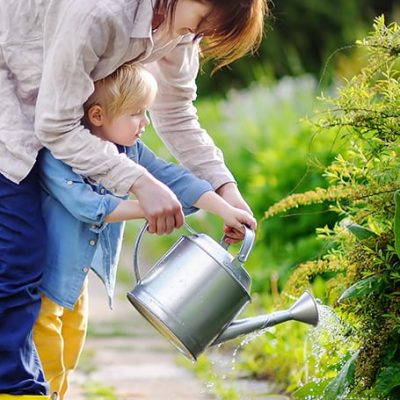 mujer ayudando a un niño a regar las plantas